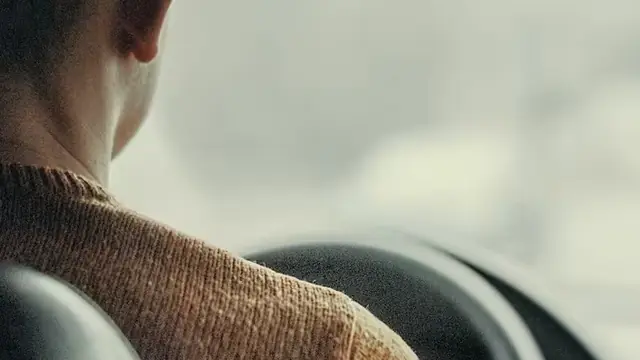 A passenger seated in the back of a private car looking out at the city